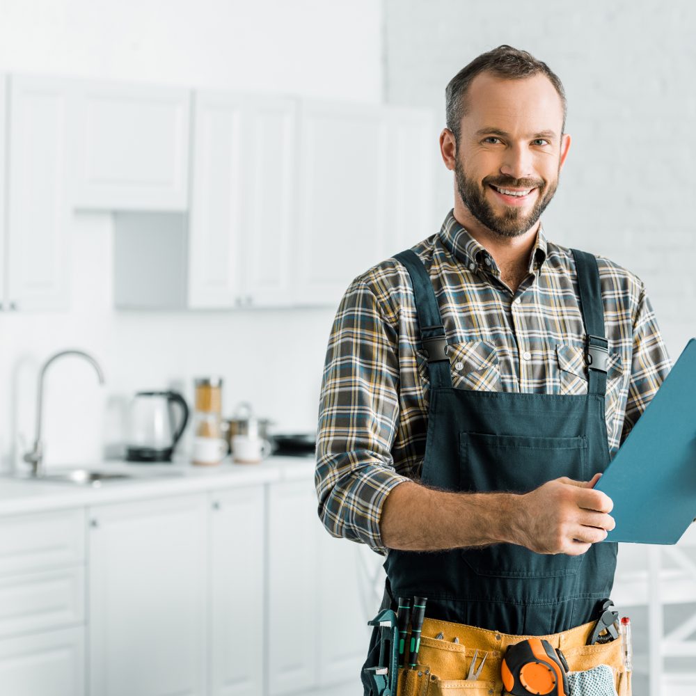 Plumber reviewing a checklist while working in clients kitchen