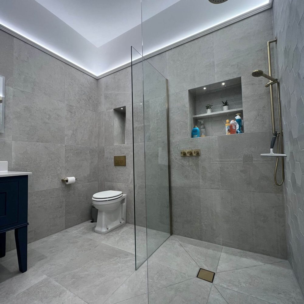 A large, clean, newly installed bathroom, with grey tiling